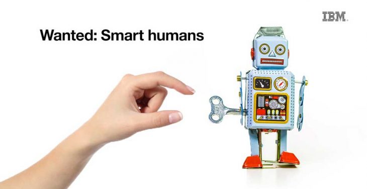 a hand winding a toy robot with the text that reads Wanted: Smart humans