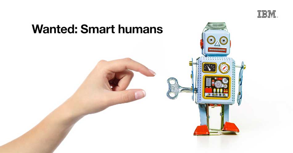 a hand winding a toy robot with the text that reads Wanted: Smart humans